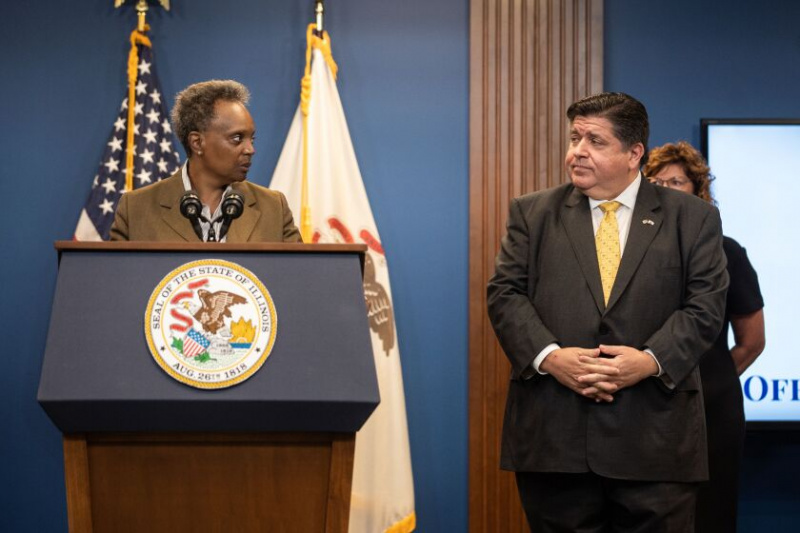   Gubernator J.B. Pritzker i burmistrz Chicago Lori Lightfoot patrzą na siebie podczas konferencji prasowej w dzielnicy Greektown, gdzie Pritzker ogłosił, że podpisał proklamację katastrofy i wezwał Gwardię Narodową Illinois do wsparcia ponad 500 migrantów wysłanych przez rząd Teksasu. Greg Abbott do Illinois, środa, 14 września.