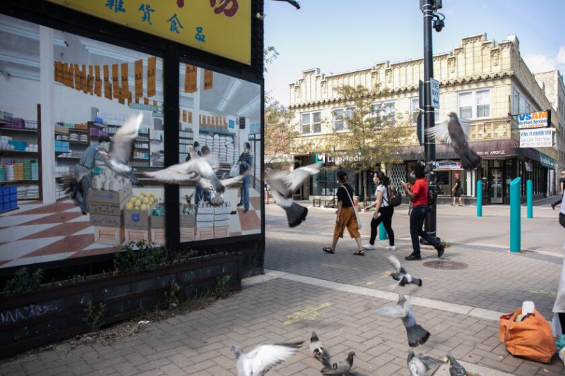   Orang ramai berjalan berhampiran mural ketika burung merpati terbang di sepanjang West Argyle Street di Uptown di North Side, Selasa, 30 Ogos.