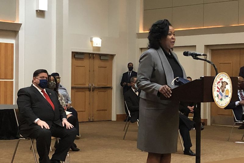 Den demokratiska delstatsrepresentanten Sonia Harper talar vid en presskonferens om Illinois Legislative Black Caucus agenda. Till vänster sitter guvernör J.B. Pritzker i en stol medan han lyssnar.