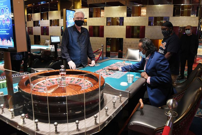 Dealer Gary Reed přihlíží, jak Tilak Fernando a Dred Phillips hrají ruletu v Bellagio Resort & Casino na Las Vegas Strip minulý týden poté, co byla nemovitost otevřena poprvé od uzavření 17. března kvůli pandemii koronaviru.