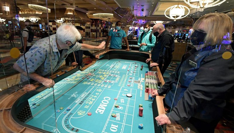 Hosté hrají kostky 4. června na stole s bezpečnostními štíty z plexiskla v Bellagio Resort & Casino na Las Vegas Strip poté, co byl objekt otevřen poprvé od 17. března, kdy byl kvůli koronaviru uzavřen.