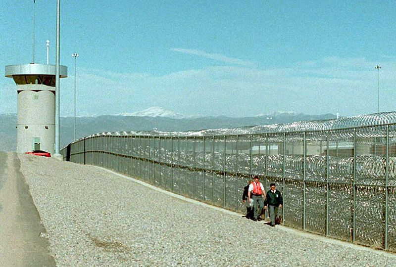 Os guardas caminham ao longo da cerca na prisão federal de segurança máxima em Florence, Colorado, onde Larry Hoover está detido.