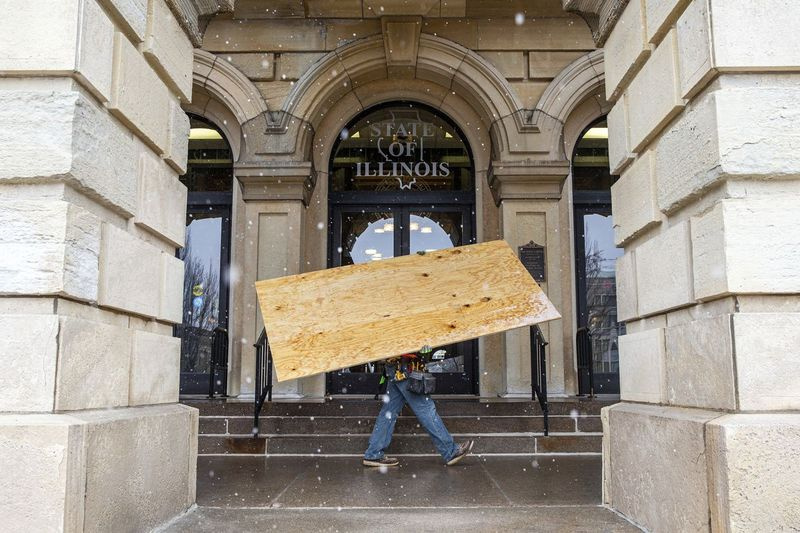 Töötajad manööverdavad reedel vineerilehed oma kohale, kui nad katavad Illinoisi osariigi kapitooliumi esimese korruse aknaid, et valmistuda võimalikeks protestideks.