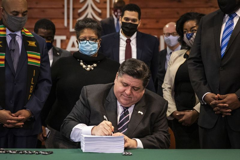 Guvernør J.B. Pritzker underskriver mandag lovforslaget om reform af strafferetsreformen ved Chicago State University, mens sponsorer og tilhængere ser på.