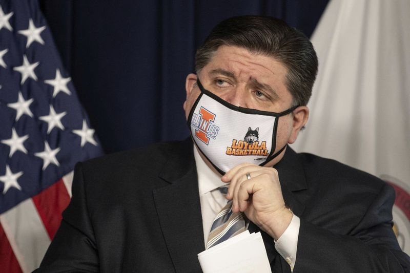 Guvernør J.B. Pritzker justerer sin maske under en torsdag pressekonference i James R. Thompson Center i Loop. Milliardæren demokrat lagde 35 millioner dollars i sin kampagnefond i sidste uge.