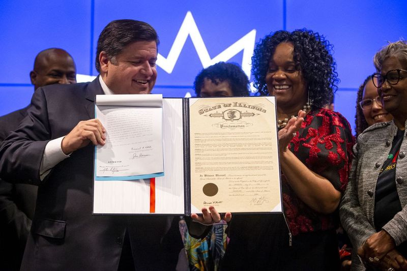 Gubernator J.B. Pritzker i przywódczyni większości w Senacie Kimberly Lightford, D-Maywood, trzymają podpisaną kopię House Bill 3992, która ustanawia Narodowy Dzień Wolności Czerwca.