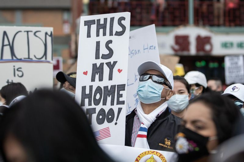 Un homme avec une pancarte indiquant This is my home too se tient parmi des centaines de personnes qui assistent à un rassemblement dans le quartier chinois pour protester contre la violence anti-asiatique, samedi après-midi.