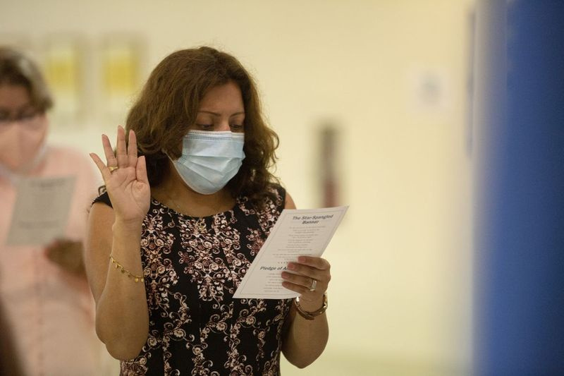 Claudia Quintero zvedá ruku pro přísahu věrnosti během pondělního naturalizačního ceremoniálu v kanceláři amerického úřadu pro občanství a přistěhovalectví South Loop.