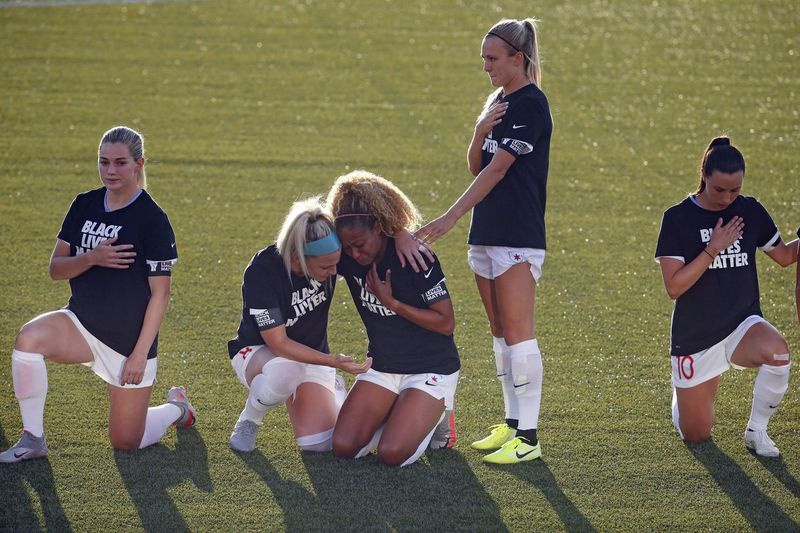 SÚBOR – Na snímke tohto 27. júna 2020 Julie Ertz z Chicaga Red Stars, druhá zľava, drží Caseyho Shorta v strede, zatiaľ čo ostatní hráči tímu kľačia počas národnej hymny pred futbalovým zápasom NWSL Challenge Cup proti Washingtonu. Spirit na štadióne Zions Bank v Herriman, Utah. Národná ženská futbalová liga revidovala svoje pravidlá týkajúce sa hymny po tom, čo väčšina hráčok pokľakla počas hymny pred úvodnými zápasmi sezóny minulý víkend na Challenge Cupe. (AP Photo/Rick Bowmer, súbor) ORG XMIT: NY158