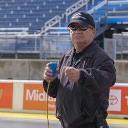 El campeón de carreras e instructor Frank Hawley se prepara para dar una señal a un corredor en la línea de salida en su escuela de carreras de resistencia.