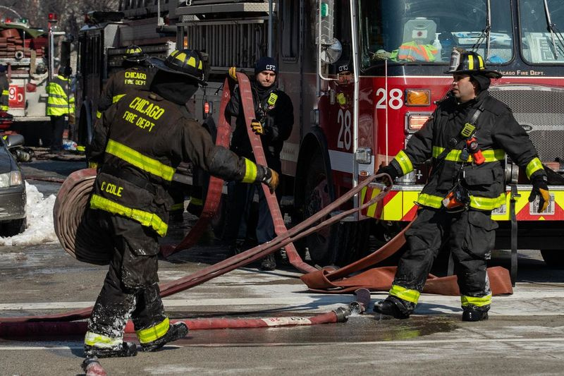 Brandmændene fra Chicagos brandvæsen bærer et hus, mens de forsøgte at slukke en ekstra-alarmbrand i Bridgeport-kvarteret i februar.