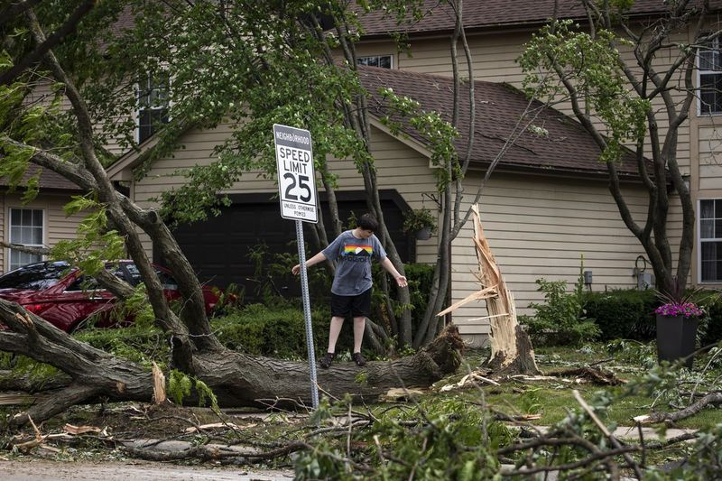 Bērns spēlē uz nokrituša koka 77. ielā netālu no Ranchview Drive Neapervilā pēc viesuļvētra, kas naktī uz pirmdienas pēcpusdienu plosījās rietumu priekšpilsētā,