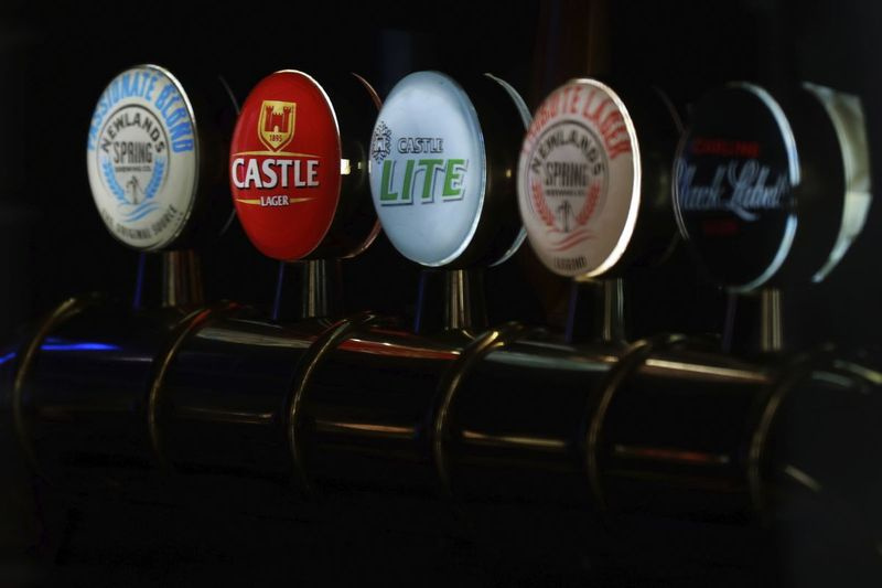 Krany do piwa marek South African Brewery, Castle, Castle Light i Black Label, są widoczne przez okno zamkniętego baru w Cape Town w RPA.