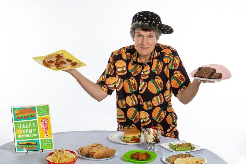 Autore Kima Zahmana 2020. gadā pozē ar savu jauno grāmatu Hamburgeros nav šķiņķa un ēdiena šķīvjus Rosvelā, Džordžijas štatā.