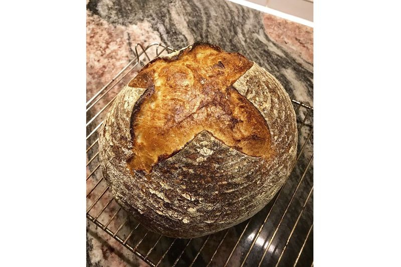 Une miche de pain au levain maison se refroidit sur une grille.
