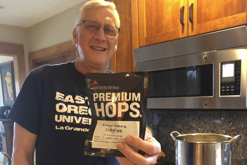 Andrew Selsky drží vrece chmeľu na domáci hefeweizen na nemecký spôsob. Homebrewing poskytuje únik z bývania v súvislosti s pandémiou COVID-19.