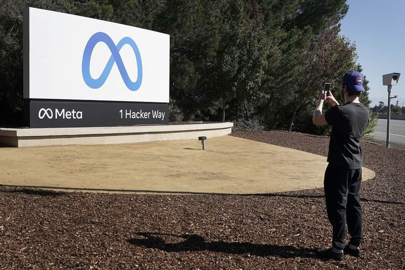 Um funcionário do Facebook tira uma foto em frente à nova placa da Meta Platforms Inc. fora da sede da empresa em Menlo Park, Califórnia.