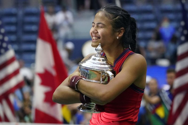 Emma Raducanu z Británie objímá mistrovskou trofej US Open poté, co ve finále ženské dvouhry porazila Leylah Fernandez z Kanady.