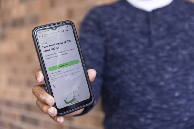   En hand som håller en mobiltelefon som visar Chime Financial-appen. Chime kallar sig 'den #1 mest älskade bankappen' och har miljontals användare, även om den också avslöjar att det är ett 'finansiellt teknikföretag, inte en bank.'