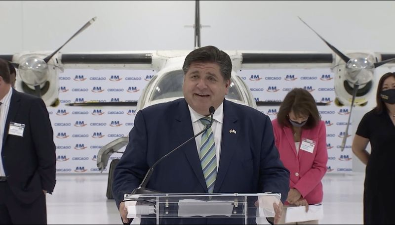 Gubernators Dž.B. Prickers trešdien runā lentes griešanas laikā jaunai aviācijas apkopes mācību iestādei Makkinlija parkā.
