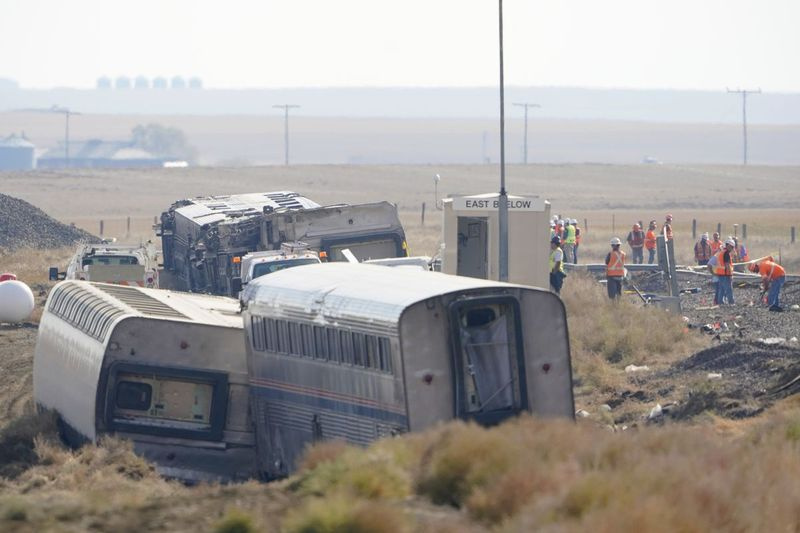 arbeiders staan ​​in de buurt van treinsporen naast gekantelde auto