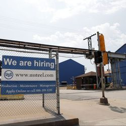 Před závodem US Steel Granite City Works ve čtvrtek 28. června 2018 v Granite City, Illinois, visí nápis s hledanou pomocí. Po zhruba dvou letech odstavení závod nedávno znovu spustil jednu ze svých dvou nečinných vysokých pecí s plánovanou druhou vrátit se online později v tomto roce. | AP Photo/Jeff Roberson