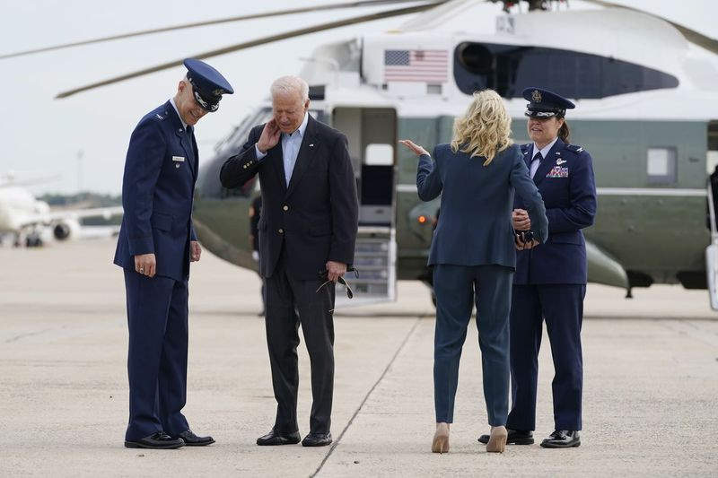 President Joe Biden borstar en cikada från hans hals när han och första damen Jill Biden går ombord på Air Force One, onsdagen den 9 juni 2021, på Andrews Air Force Base, Md.