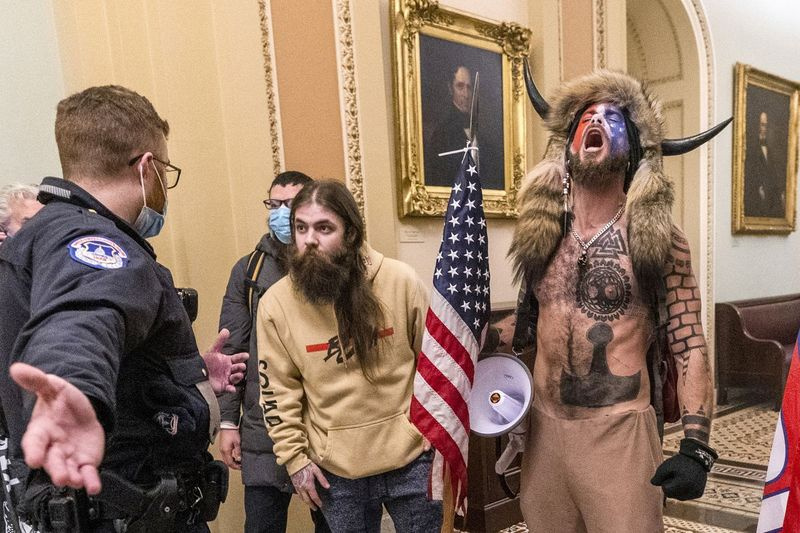 Anhängare av president Donald Trump, inklusive Jacob Chansley, höger med pälsmössa, konfronteras av amerikanska Capitol-poliser utanför senatens kammare inne i Capitolium under capitolupploppet i Washington den 6 januari 2021. Chansley dömdes onsdagen den nov. 17, 2021, till 41 månaders fängelse för hans brottsdom för att ha hindrat ett officiellt förfarande.