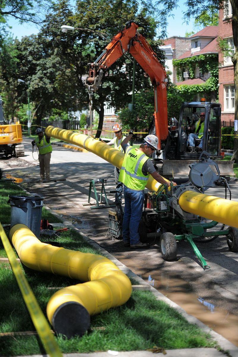 Na fotografii pořízené loni v létě stojí dělníci nad novými plynovody, které mají být instalovány na ulici Albany Park. Výdaje na projekt v průběhu let narůstaly a mohly by nakonec stát 8 až 11 miliard dolarů.