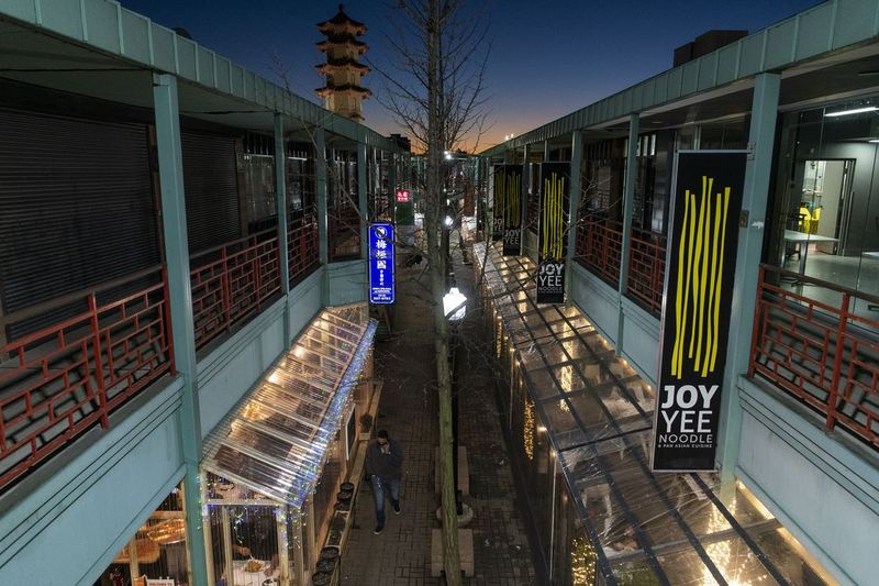Een man loopt langs het openluchtwinkelcentrum van Chinatown Square.