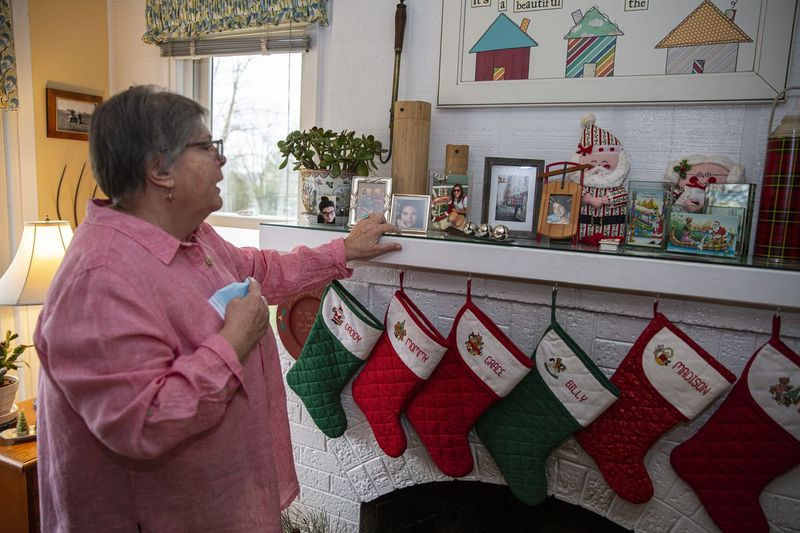 Julie Heiderman, die an einem mit Weihnachtsstrümpfen geschmückten Kaminsims steht, betrachtet Fotos ihrer Tochter Bernice, die auf dem Kaminsims zu sehen sind. Es ist die dritte Ferienzeit seit Bernices Tod.