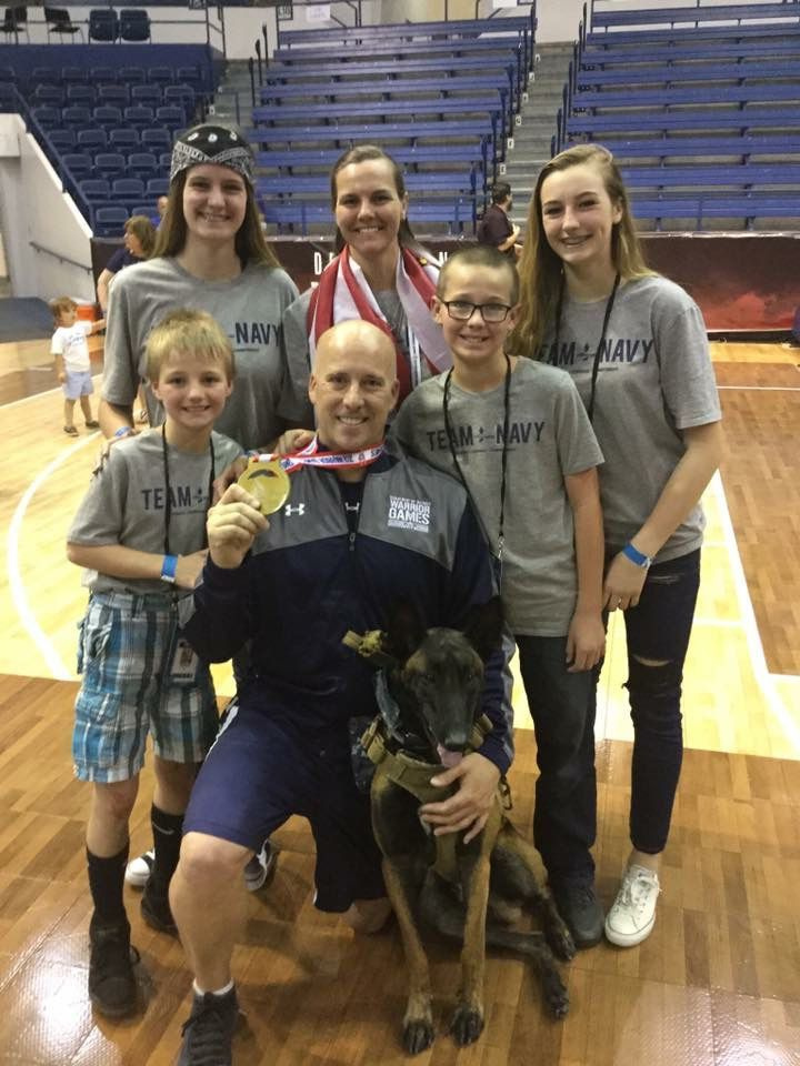 Carl Hill com sua família e cão de serviço no Warrior Games 2018 do Departamento de Defesa para militares feridos em Colorado Springs, Colorado. Mais tarde, Hill teve problemas para acessar o dinheiro do projeto de lei pós-11 de setembro para a educação universitária de uma filha.