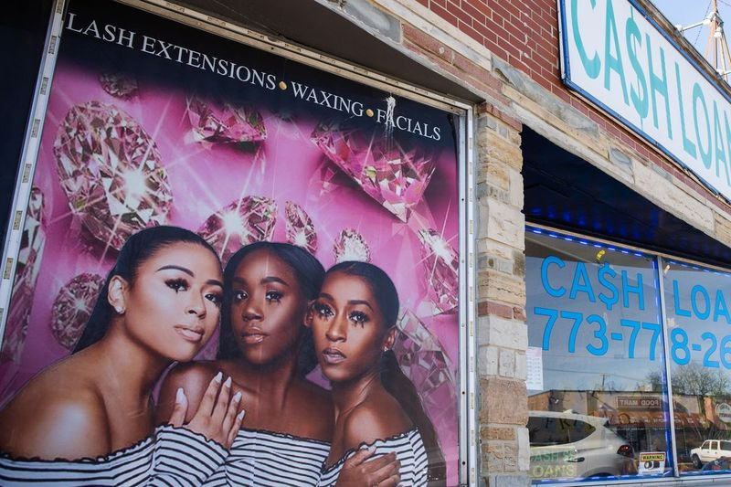 En lånebutik i stadsdelen Ashburn på Chicagos South Side. En reklam för skönhetsprodukter med tre unga svarta kvinnor finns på tegelväggen bredvid lånebutikens ytterdörr. En analys av 2019 års låntagardata fann ett överflöd av högräntelån i majoriteten av svarta stadsdelar. Branschgrupper säger att de lånar ut pengar till människor som inte kvalificerar sig för traditionella banklån.
