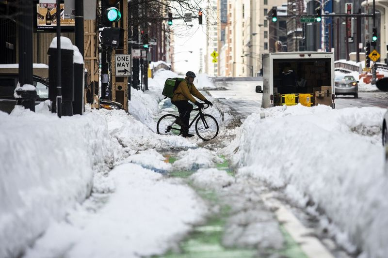 Cyklista projíždí kolem cyklostezky v ulicích West Lake a North Dearborn v Loop, jeden den poté, co části Chicaga zavalila největší zimní bouře ve městě v této sezóně, ve středu 17. února 2021.
